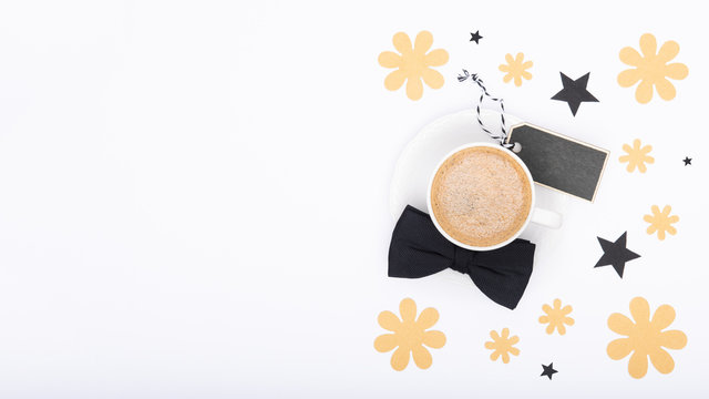 Happy Father's Day Background. Cup of coffee and black bow tie on white background flat lay. Floral Fathers day still life setup.