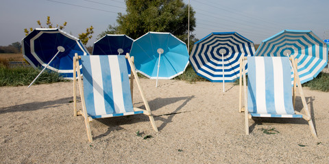 white and blue scene in sand beach with umbrella and relax chair