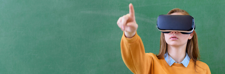 Teenager female student wearing virtual reality glasses in classroom at school. Innovative teaching...