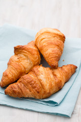 Tasty buttery croissants on old wooden table.