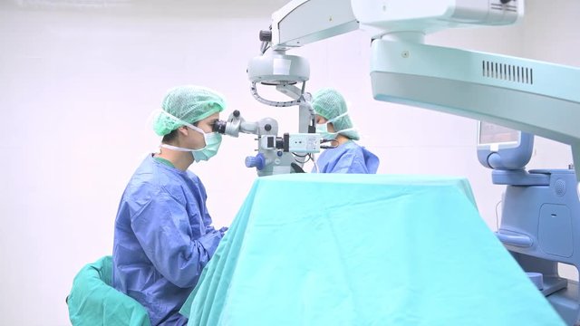 Surgeon operating lasik machine. Young white male surgeon operating lasik machine on a senior patient. Advance eye surgery concept. Sliding dolly shot.