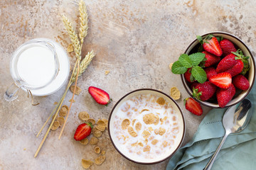 Healthy breakfast - whole grain flakes, milk and fresh strawberries on stone or slate background. The concept of nutrition health. Copy space, top view flat lay background.