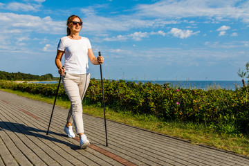 Nordic walking - middle-age woman working out in city park