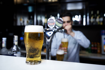 A glass of beer on a blurry bar background.