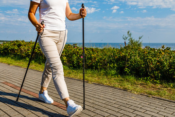 Nordic walking - middle-age woman working out in city park