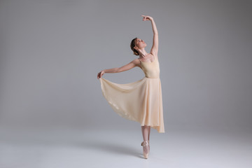 Timeless interpretation of life! Full length photo of the young beautiful ballerina fulfilling movements on the light background. © stacestock
