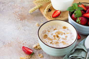 Healthy breakfast - whole grain flakes, milk and fresh strawberries on stone or slate background. The concept of nutrition health. Copy space.