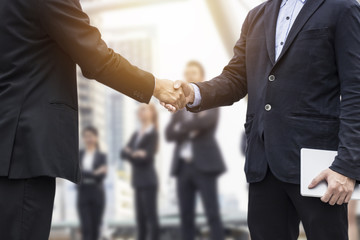 Fototapeta na wymiar Successful negotiating business concept, Businessmen shaking hands after finishing meeting or setting goals and planning way to success in front of team work
