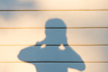 photographer shadow on concrete wall background in the evening time, half body of shadow