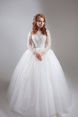 Fototapeta premium Lovely young woman bride in lavish wedding dress. Light background.