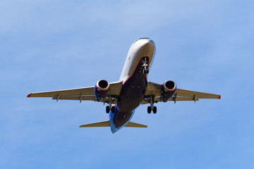 Bottom view of a dark silhouette of flying passenger aircraft a background of blue sky