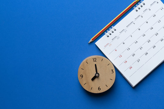 close up of calendar, clock and pencil on the blue background, planning for business meeting or travel planning concept