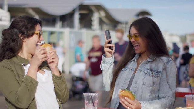 Excited Tourist Takes A Photo Of Her Friend Posing With Her Burger For Social Media (Shot On Red Scarlet-W Dragon In 4K, Slow Motion)