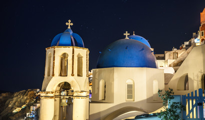 Scenic view of traditional cycladic white houses and blue domes in Oia village, Santorini island, Greece at night