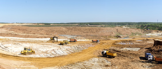 Panorama of the quarry. Extraction of sand in the quarry. Backhoe loading sand into dump trucks.