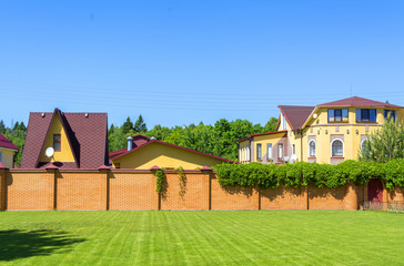 Beautiful country house with garage behind a brick fence.