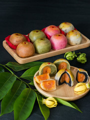 Closeup chinese cake in wooden plate with green Ylang-Ylang leaf on dark background