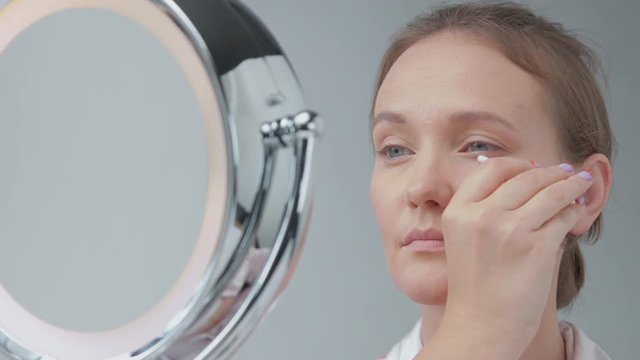 young woman using a cotton swab correcting eye and brow zones