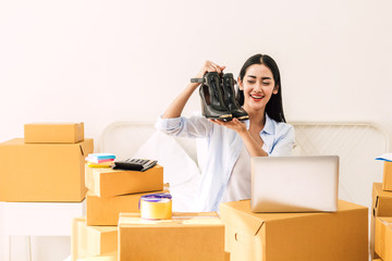 Young woman freelancer working sme business online shopping and packing shoes with cardboard box on bed at home - Business online shipping and delivery concept