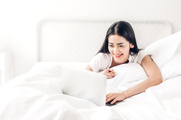 Happy woman relaxing and using digital laptop computer on the bed at home.woman checking social apps and working with smartphone