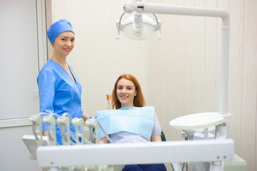 dentist in dental office talking with female patient and preparing for treatment.
