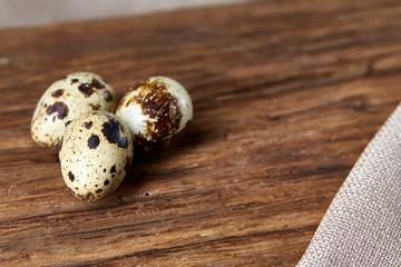 Obraz premium Group of three quail eggs on a wooden table, top view, close-up, selective focus, copy space.