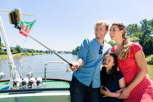 Happy family on river cruise with selfie stick in summer