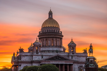 Saint Isaac's Cathedral in the square, in St. Peterburg in the evening on a bright orange sunset sky.