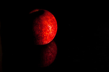 The apple red on the glass, black background.