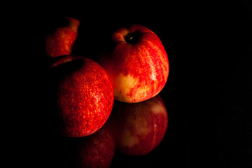 Fototapeta na wymiar The apple red on the glass, black background.