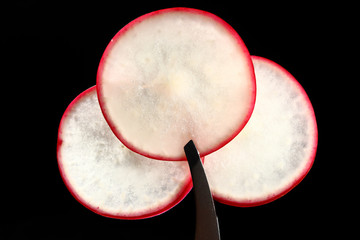 composition of pieces of fresh radishes on a black background