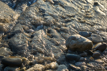 pebble stones on the sea beach, the rolling waves of the sea with foam