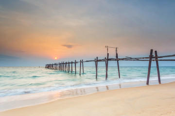 Beautiful sunset on the beach with wooden bridge in Phuket, Thailand. Phuket is located in Southern Thailand. It is the biggest island of Thailand and sits on the Andaman Sea.