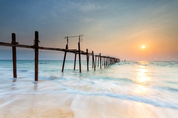 Beautiful sunset on the beach with wooden bridge in Phuket, Thailand. Phuket is located in Southern Thailand. It is the biggest island of Thailand and sits on the Andaman Sea.