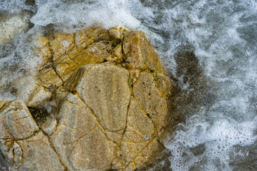 pebble stones on the sea beach, the rolling waves of the sea with foam