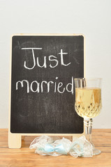 A blackboard with just married on it displayed with a glass of champagne and a garter
