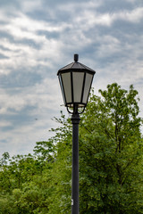 Fototapeta na wymiar Old single street lamp in front of a cloudy sky in summer 