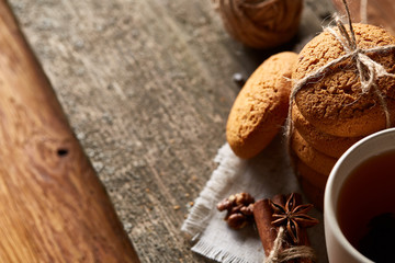 Traditional Christmas tea concept with a cup of hot tea, cookies and decorations on a wooden table, selective focus
