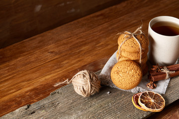 Traditional Christmas tea concept with a cup of hot tea, cookies and decorations on a wooden table, selective focus