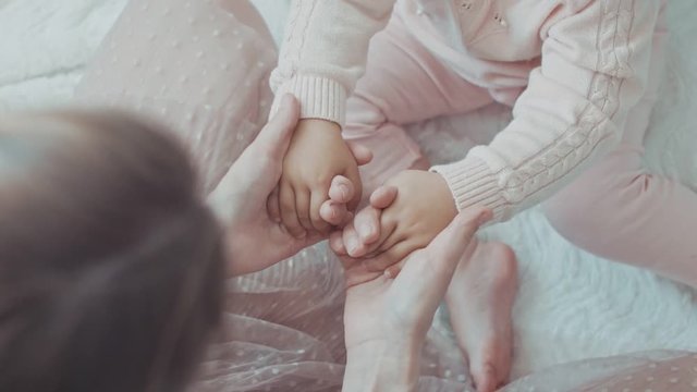 Parent holding babys hands. Top view