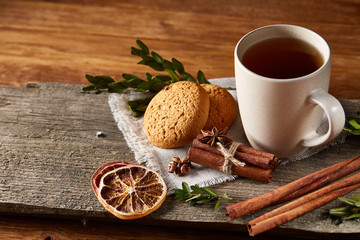 Traditional Christmas tea concept with a cup of hot tea, cookies and decorations on a wooden table, selective focus