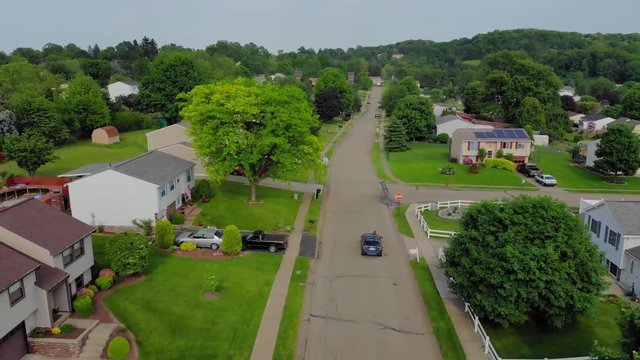 An aerial flyover view of cars traveling on the streets in a typical Pennsylvania residential neighborhood. Pittsburgh suburbs.  	