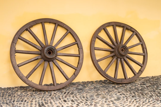 Two old wooden wheels of the cart on a floor of gallets