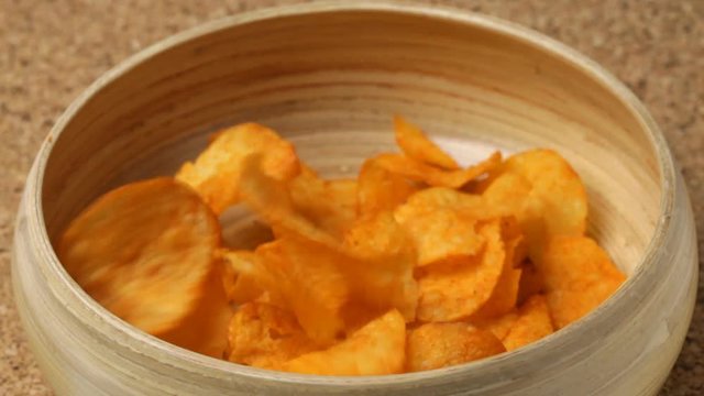 Close up of paprika potato chips falling into bowl. No sound.