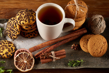 Traditional Christmas tea concept with a cup of hot tea, cookies and decorations on a wooden table, selective focus