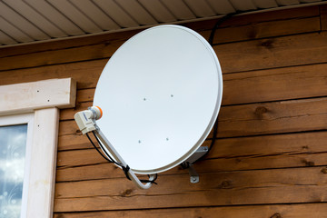 Satellite dish on the wall of the house.