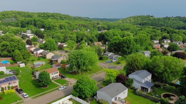 A slowly rising aerial establishing shot of a typical Pennsylvania residential neighborhood on a sunny summer day. Pittsburgh suburbs.  	