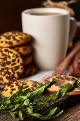 Christmas composition with pile of cookies, cinnamon and dried oranges on wooden background, close-up.