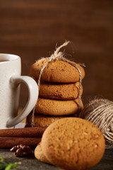 Christmas composition with pile of cookies, cinnamon and dried oranges on wooden background, close-up.