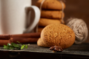 Traditional Christmas tea concept with a cup of hot tea, cookies and decorations on a wooden table, selective focus